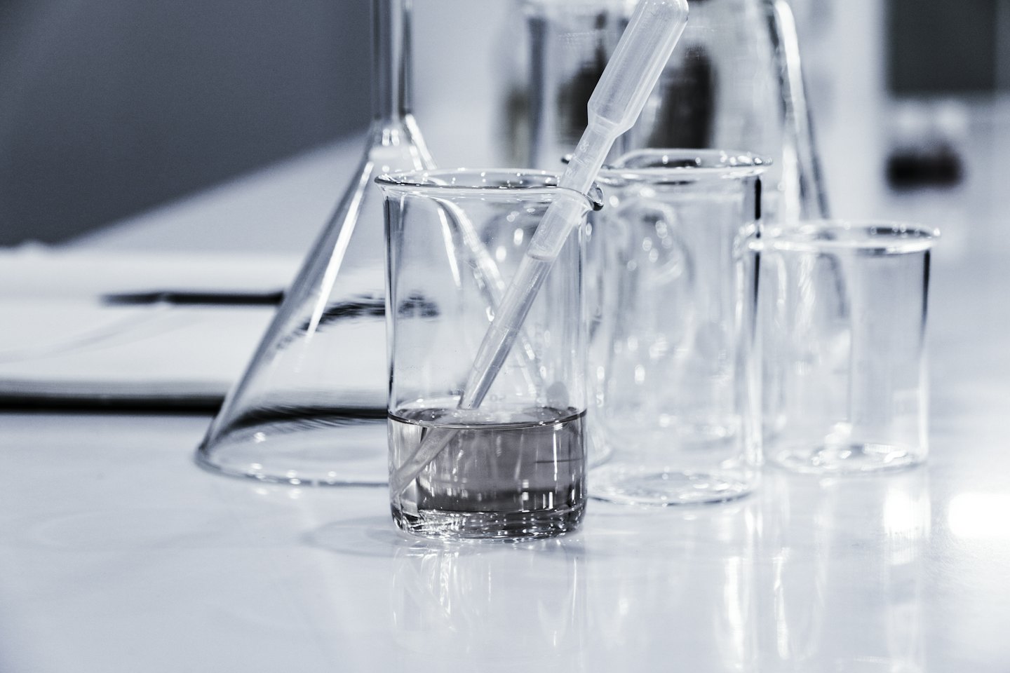 Beakers and funnel on a lab surface with liquid in one beaker.
