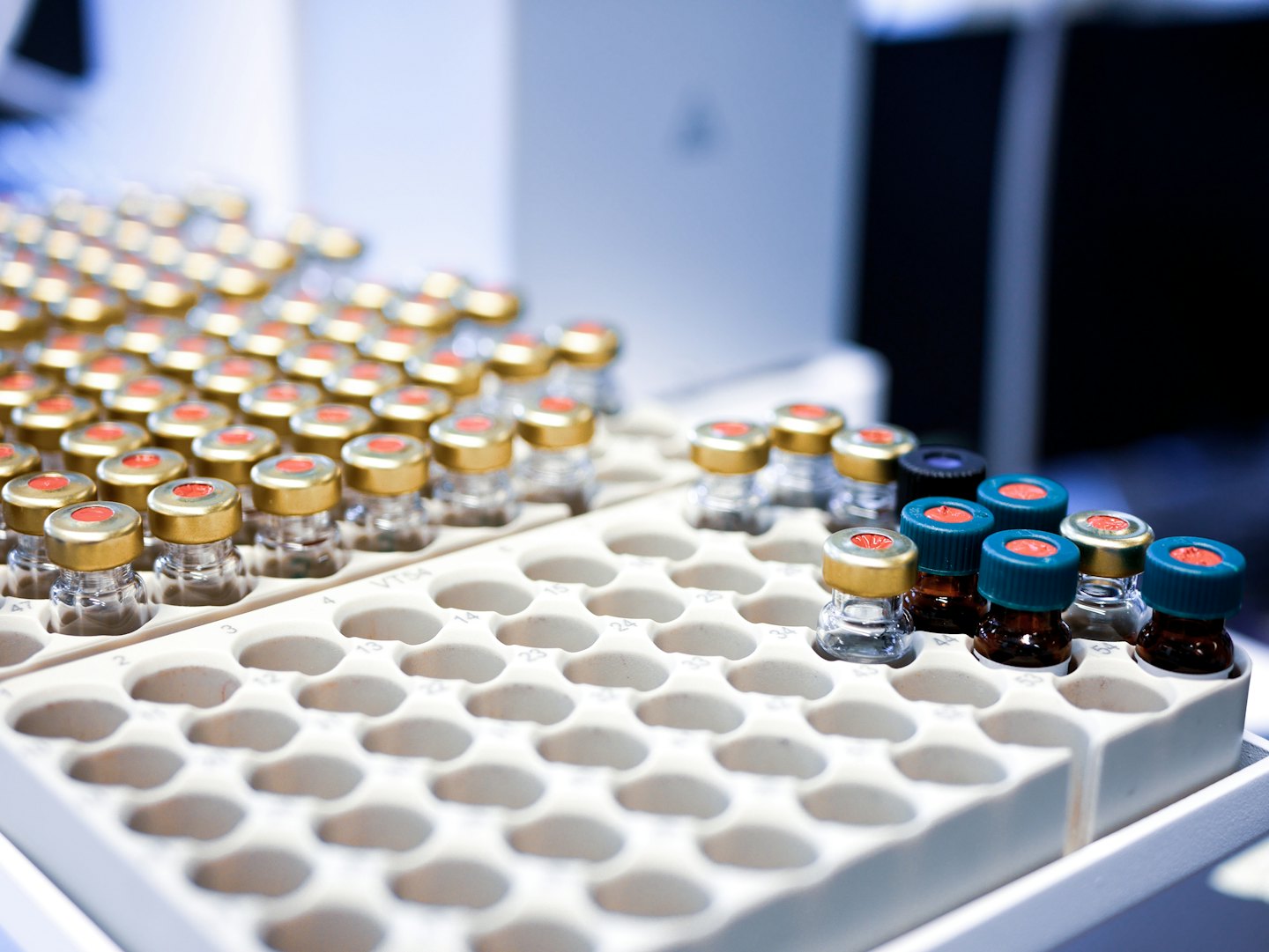 Small glass vials filled with colorful liquids in a lab tray.