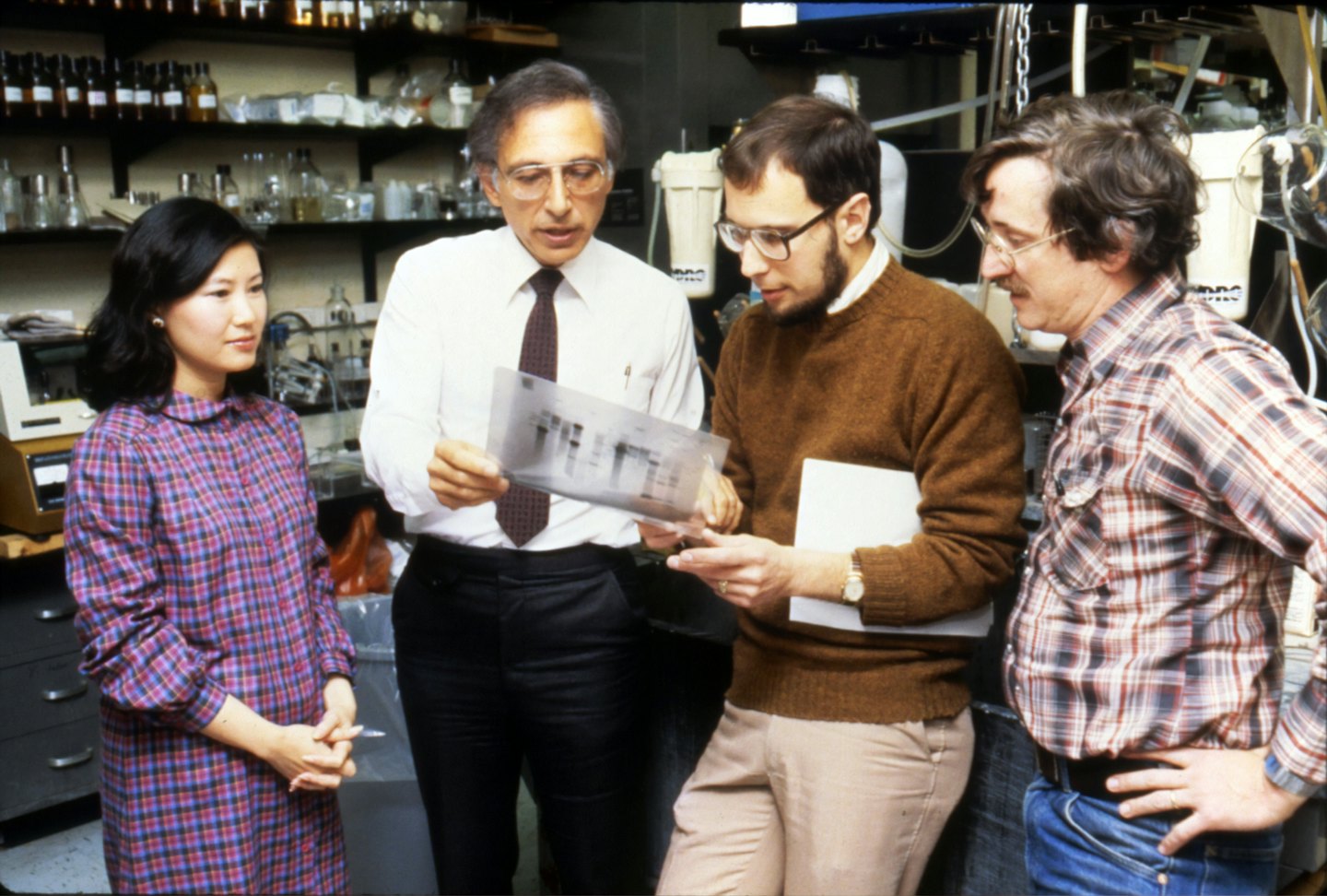 Scientists examine a gel image together in a lab.