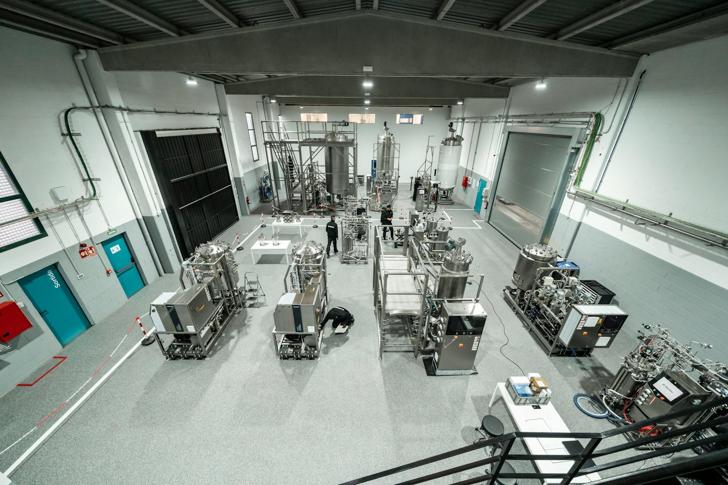 Two men work near bioreactors in a large, modern laboratory.