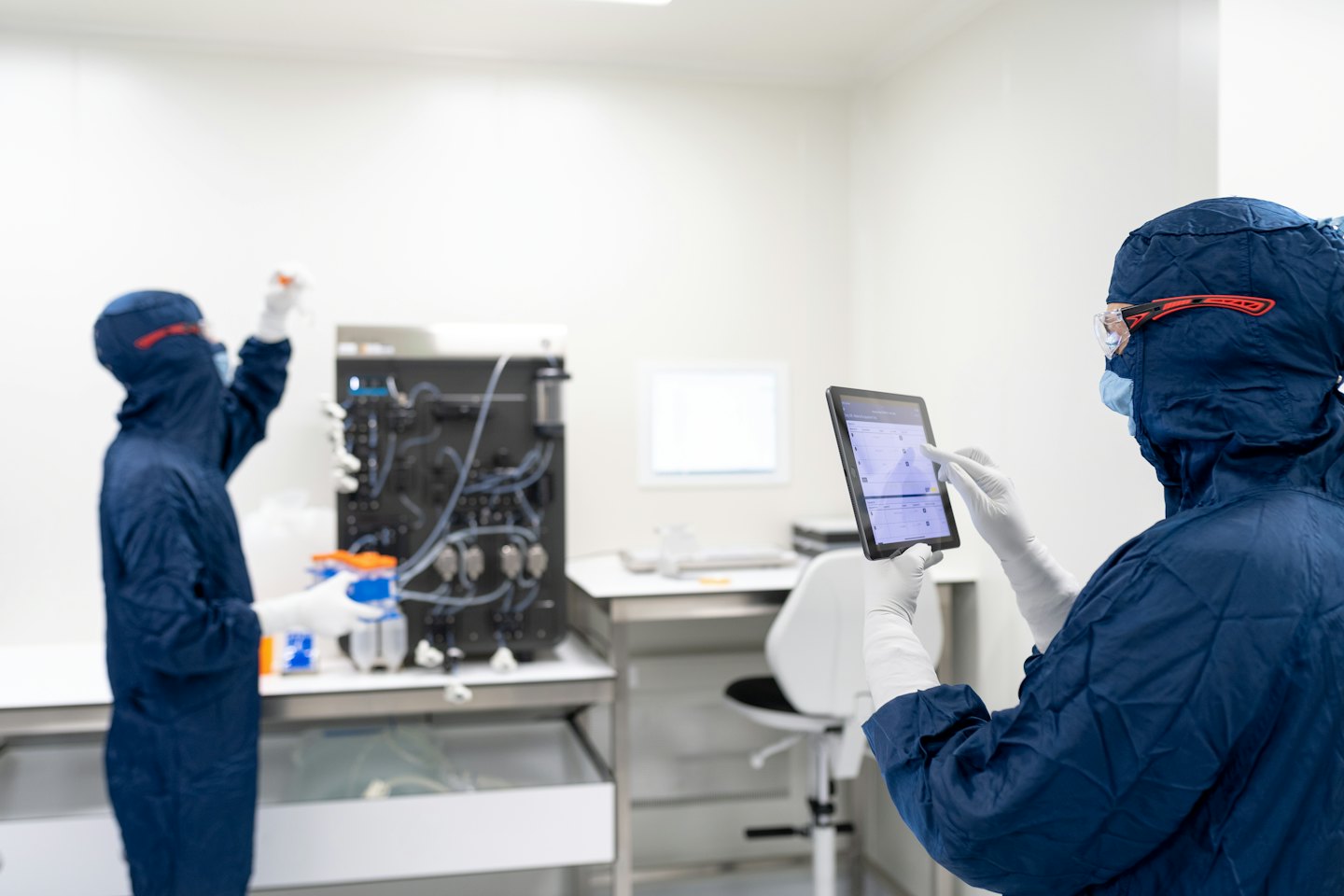 Scientists in cleanroom suits working with lab equipment.